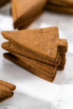 Süslenmemiş zencefilli kurabiye yığınları kraliyet kreması ile süslenmeye hazır..