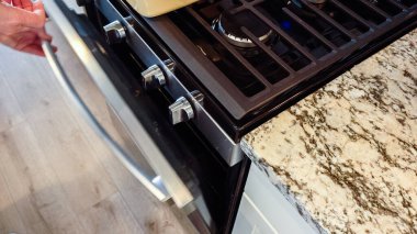 Modern beyaz bir mutfakta, teriyaki somonu pişirmek için dikkatlice fırına yerleştiriliyor..