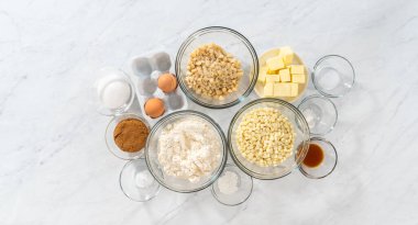 Düz yatıyordu. Beyaz çikolatalı macadamia fındığı hazırlamak için cam karıştırma kabında ölçülmüş malzemeler..