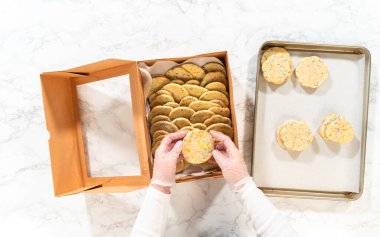 Düz yatıyordu. Kadın özenle, hamur karışımı şekerlemelerle dolu şekerli kurabiyeleri kırsal kahverengi bir karton kutuya yerleştiriyor..