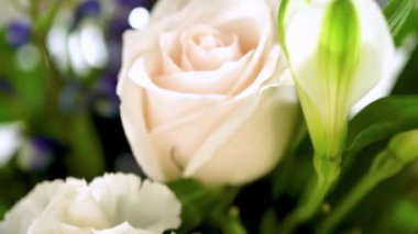 Taze beyaz güllerin ve çeşitli çiçeklerin bulunduğu büyüleyici bir buket, zarif bir vazoda düzenlenmiş, zamansız bir güzellik yayıyor..