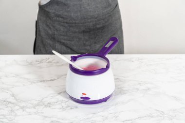 Panda şeklindeki kurabiyeler için çikolatalı fiyonk yapmak için şekerleme kabında pembe çikolata parçacıkları eritiyorum..