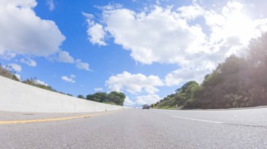 Açık bir kış gününde, bir araba, Santa Maria, California yakınlarındaki 101. Otoyol boyunca yeşil ve altın renkli bir karışımla çevrili, parlak mavi bir gökyüzünün altında sorunsuzca seyahat eder..