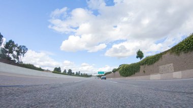 Açık bir kış gününde, bir araba, Santa Maria, California yakınlarındaki 101. Otoyol boyunca yeşil ve altın renkli bir karışımla çevrili, parlak mavi bir gökyüzünün altında sorunsuzca seyahat eder..