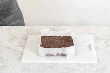 Parşömenle kaplı kare bir peynirli kek tavasından çikolatalı macadamia şekerlemesi çıkarıyorum..