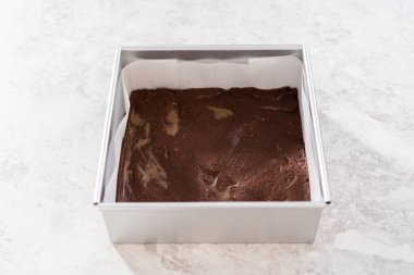 Çubuk şekerleme hazırlamak için kareli peynirli kek kalıbını parşömen kağıdıyla dolduruyorum..