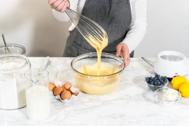 Cam kasenin içindeki malzemeleri birleştirmek, lezzetli bir vanilyalı kek hazırlamak için ustalıkla çırpmak..