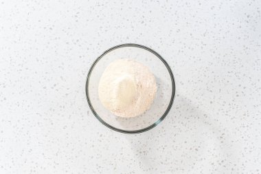 Flat lay. Mixing dry ingredients with a hand whisk in a large glass mixing bowl to bake a simple vanilla bundt cake.