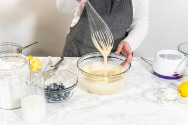 Cam bir kasenin içindeki bileşenleri birleştirmek, bir çırpıcıyla karıştırmak, limonlu-yabanmersinli kek hazırlamak..