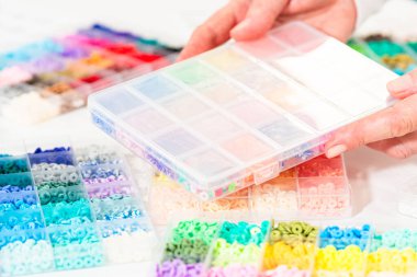 Beyaz bir masaya yerleştirilmiş çeşitli kil boncuk kutuları yaratıcı çocukların el sanatları projesini bekliyor..