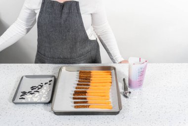 Çubuk krakerleri erimiş çikolataya batırıp Cadılar Bayramı 'nda çikolata kaplı çubuk kraker yapmak..