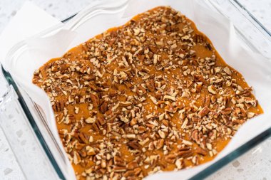 Kabak aromalı şekerleme hazırlamak için parşömen kağıdıyla kaplanmış kare cam fırın tavasına şekerleme dökülüyor..