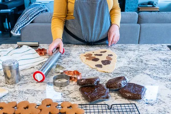 In a contemporary white kitchen, gingerbread cookie dough is skillfully rolled out, setting the stage for a delightful holiday treat.