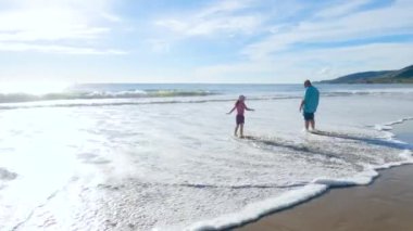 California 'da bir baba ve kızı, El Capitan Eyalet Plajı' nın ıssız kumları boyunca sakin bir kış yürüyüşünü paylaşıyor..