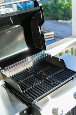 Yakından bakıldığında, banliyödeki bir evin balkonunda ilk açık hava yemek pişirme macerasını bekleyen iki ocaklı ızgaranın bozulmamış ızgarasını gösteriyor..