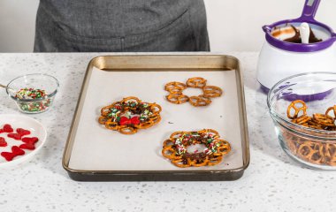 Dipping pretzels twists into melted chocolate to make a chocolate pretzel Christmas wreath.