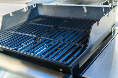 Yakından bakıldığında, banliyödeki bir evin balkonunda ilk açık hava yemek pişirme macerasını bekleyen iki ocaklı ızgaranın bozulmamış ızgarasını gösteriyor..