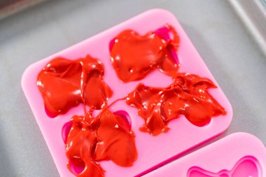 Flat lay. Filling bow silicone chocolate mold with melted chocolate to make a chocolate pretzel Christmas wreath.