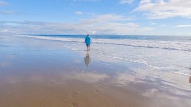 California 'da bir baba ve kızı, El Capitan Eyalet Plajı' nın ıssız kumları boyunca sakin bir kış yürüyüşünü paylaşıyor..