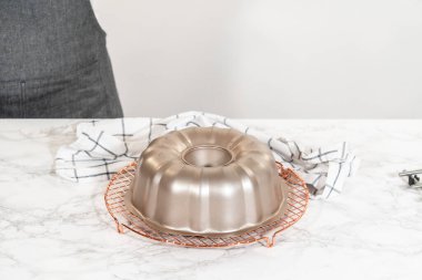 Chocolate Bundt Pastası dikkatlice tavadan çıkartılır. Yuvarlak soğutma rafına yerleştirilir. Kusursuz bir sunum ve hoş bir hoşgörü için hazırlanır..