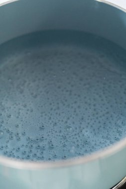 Boiling water in a cooking pot to prepare chocolate pistachio fudge.