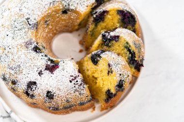 Taze pişmiş limonlu yaban mersinli kek dilimliyorum. Pudra şekerli..