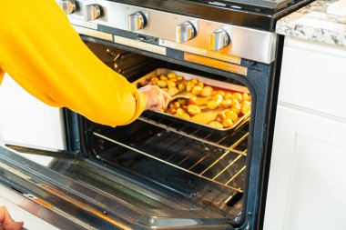 Modern bir mutfakta, yarıya indirilmiş, çok renkli mermer patatesler silikon kaplamalı bir tavaya yerleştirilir. Kızartma işlemi mutfağı ağız sulandırıcı bir aromayla dolduruyor.