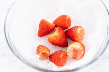 Taze yıkanmış ve kurutulmuş çilekler kağıt havluyla kaplı cam bir kasede dikkatlice düzenlenir. Atıştırmaya ya da daha fazla kullanılmaya hazır hale getirilir..