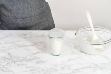 Şekerli kurabiyeleri süslemek için boru torbalarına ev yapımı kraliyet kreması aktarılıyor..