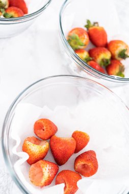 Taze yıkanmış ve kurutulmuş çilekler kağıt havluyla kaplı cam bir kasede dikkatlice düzenlenir. Atıştırmaya ya da daha fazla kullanılmaya hazır hale getirilir..