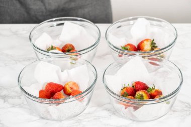 Taze yıkanmış ve kurutulmuş çilekler kağıt havluyla kaplı cam bir kasede dikkatlice düzenlenir. Atıştırmaya ya da daha fazla kullanılmaya hazır hale getirilir..