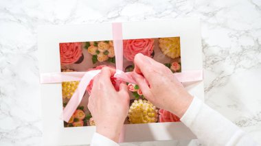 Düz yatıyordu. Bir kadının ellerinde, her biri canlı güller ve krema kaplamasından yapılmış lalelerle süslenmiş gurme keklerle dolu beyaz bir kağıt kutu nazikçe kapatılıyor..