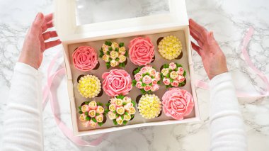 Düz yatıyordu. Bir kadın nazikçe beyaz bir kağıt kutuyu açar, içinde her biri canlı gülleri ve laleleri taklit etmek için tasarlanmış tereyağlı kremayla süslenmiş gurme keklerden oluşan bir set açar..