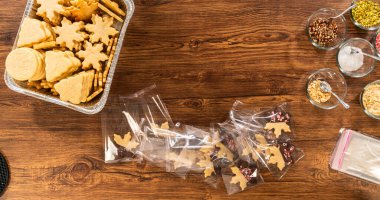 Dikkatlice paketlenmiş Noel kurabiyeleri, çikolataya batırılmış ve şeffaf selofan ambalajla sunulmuş, bayram hediyesi olarak mükemmel..