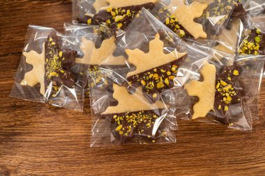 Dikkatlice paketlenmiş Noel kurabiyeleri, çikolataya batırılmış ve şeffaf selofan ambalajla sunulmuş, bayram hediyesi olarak mükemmel..