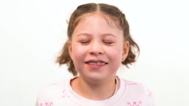 Neşeli bir anda, büyüleyici bir gülümseme ile büyüleyici küçük bir kız kameraya ışıldıyor, neşeli gökkuşağı renkli tellerini gösteriyor, bu da onun gençliğine ekstra bir parıltı katıyor.