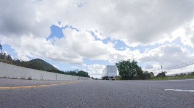 Açık bir kış gününde, bir araba, Santa Maria, California yakınlarındaki 101. Otoyol boyunca yeşil ve altın renkli bir karışımla çevrili, parlak mavi bir gökyüzünün altında sorunsuzca seyahat eder..