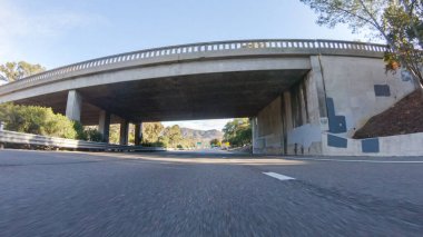 Kış günü San Luis Obispo, Kaliforniya yakınlarındaki ikonik 1. Otoyol boyunca bir araba gider. Çevresindeki manzara kahverengimsi ve bastırılmış, dalgalı tepeler ve kıyı şeritleriyle