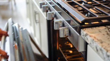 Modern bir mutfak ortamında, genç bir adam şu anda fırında baharatlı gökkuşağı patatesi kızartılarak lezzetli bir yemeğe doğru önemli bir adım atıyor..