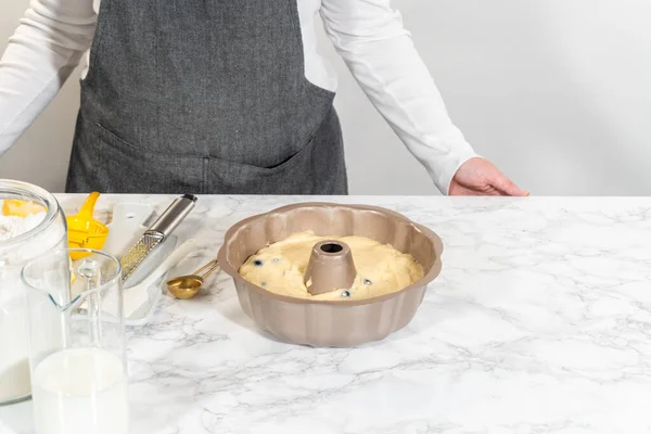 Delicately transferring the cake batter into the pre-greased bundt cake pan, setting the stage for a successful baking process.