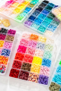 Beyaz bir masaya yerleştirilmiş çeşitli kil boncuk kutuları yaratıcı çocukların el sanatları projesini bekliyor..