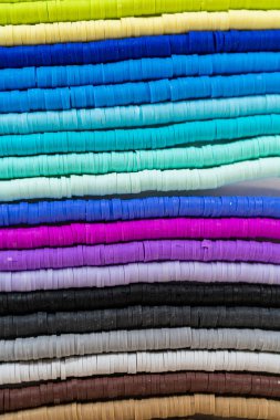 Beyaz bir masadaki renklere göre düzenlenmiş canlı bir kil boncuk koleksiyonu genç zanaatkarlara kendi eşsiz bileziklerini yapmaları için ilham vermeye hazır..