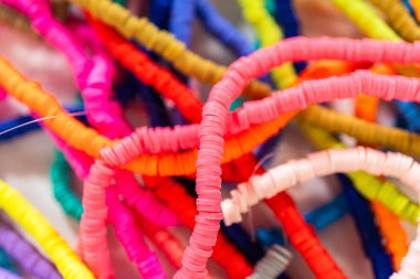 Beyaz bir masadaki renklere göre düzenlenmiş canlı bir kil boncuk koleksiyonu genç zanaatkarlara kendi eşsiz bileziklerini yapmaları için ilham vermeye hazır..