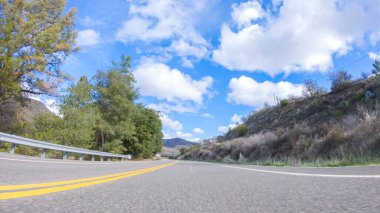 Araç, parlak güneşin altında Cuyama Otoyolu boyunca ilerliyor. Çevresindeki manzara, ışık saçan güneş ışığıyla aydınlanır ve araba seyahat ederken güzel ve davetkar bir sahne yaratır.