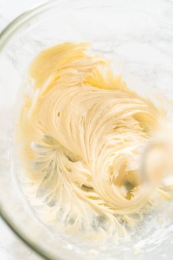 Mayasız tarçınlı çörekler için krem peynirli krema yapmak için karıştırma kabındaki malzemeleri karıştırıyorum..