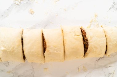 Tarçın ile doldurulmuş rulo ekmek hamuru ve daha küçük rulolara doğranmış fındıklar tarçınsız kek pişirmek için..