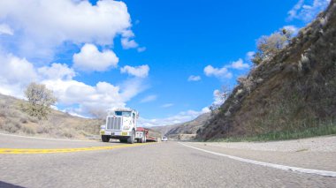 Santa Maria, California, ABD-6 Aralık 2022-Araç, parlak güneşin altında Cuyama Otoyolu boyunca ilerliyor. Çevresindeki manzara, ışık saçan güneş ışığıyla aydınlanır.