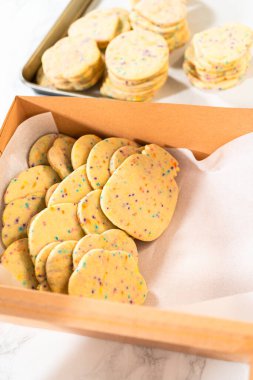 Kadın özenle, hamur karışımı şekerlemelerle dolu şekerli kurabiyeleri kırsal kahverengi bir karton kutuya yerleştiriyor..