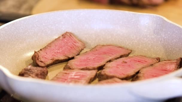 在一个斑斑的陶瓷锅里翻滚着多汁的中罕见牛排条 — 图库视频影像