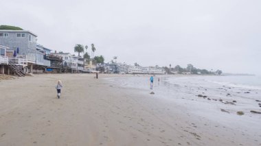 Los Angeles, California, ABD-4 Aralık 2022-POV-Yürürken Miramar Sahili, California kıyılarında bulutlu kış gökyüzü sakin ve yansıtıcı bir atmosfer yaratır..